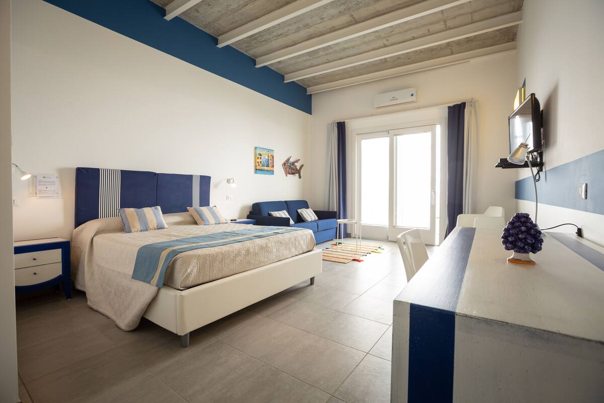 Un dormitorio con cama, escritorio, silla y ventana.