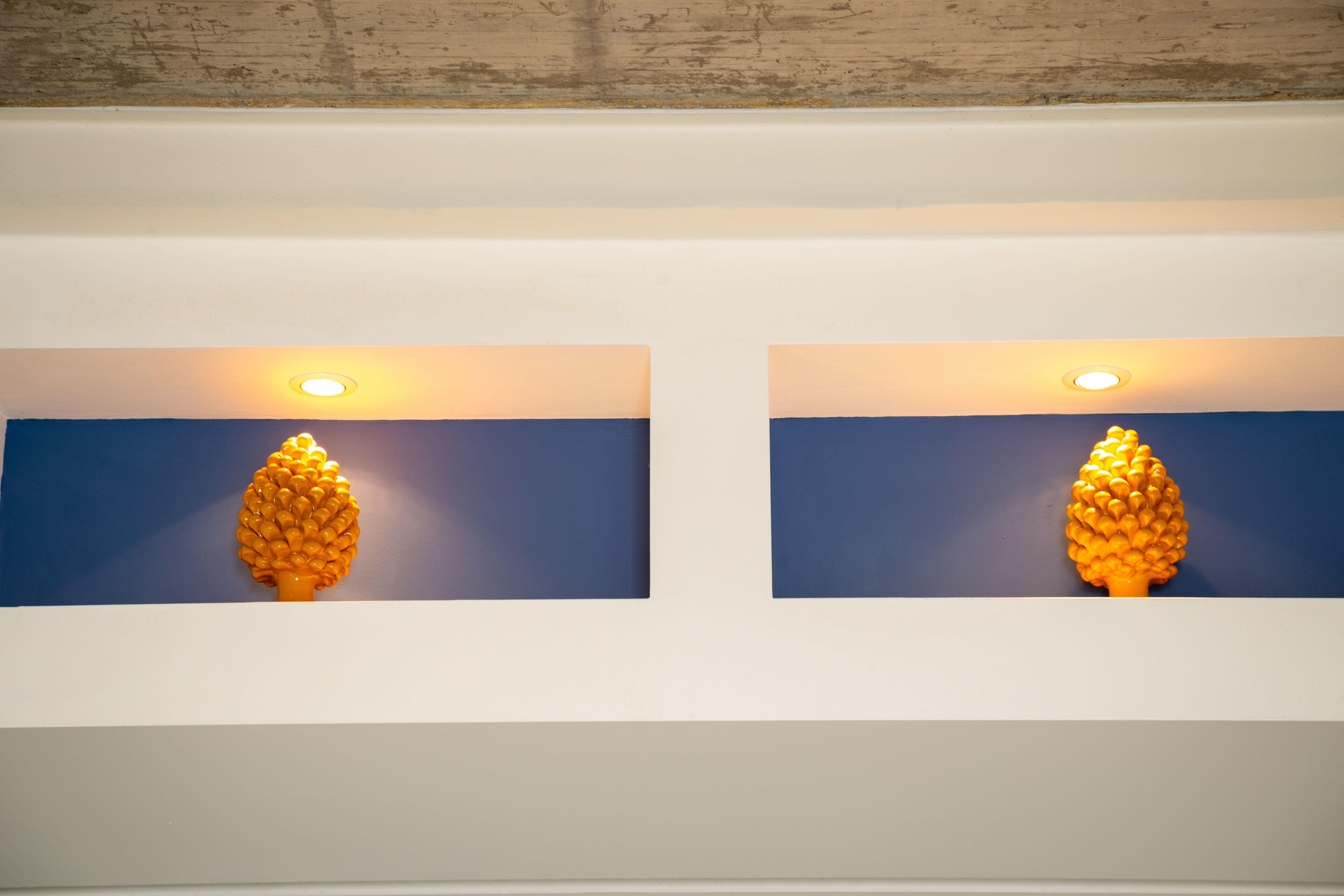 Two wall-mounted light fixtures with a pineapple design against a blue and white background.