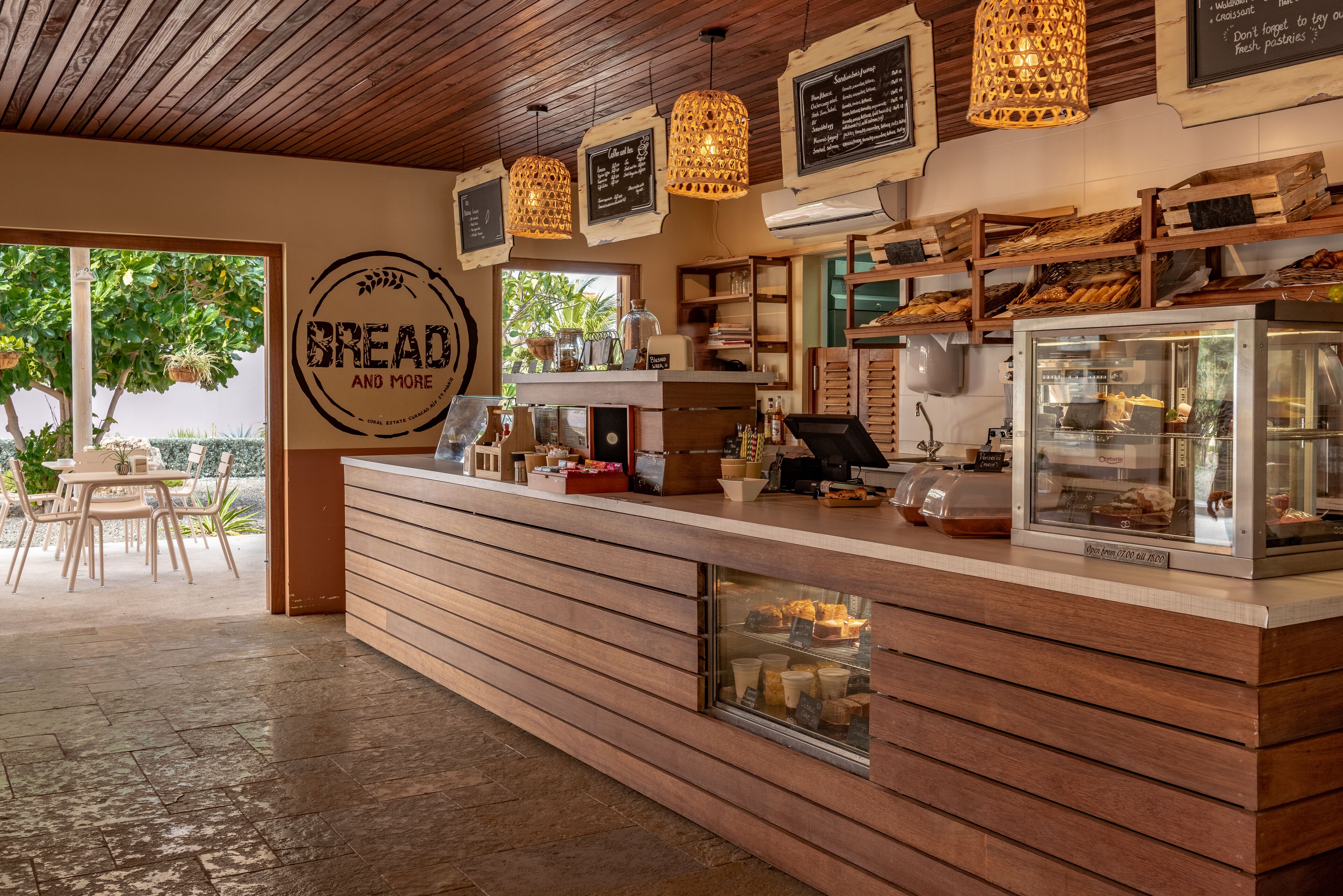 A bakery counter with wooden slats, hanging lights, and a display case.