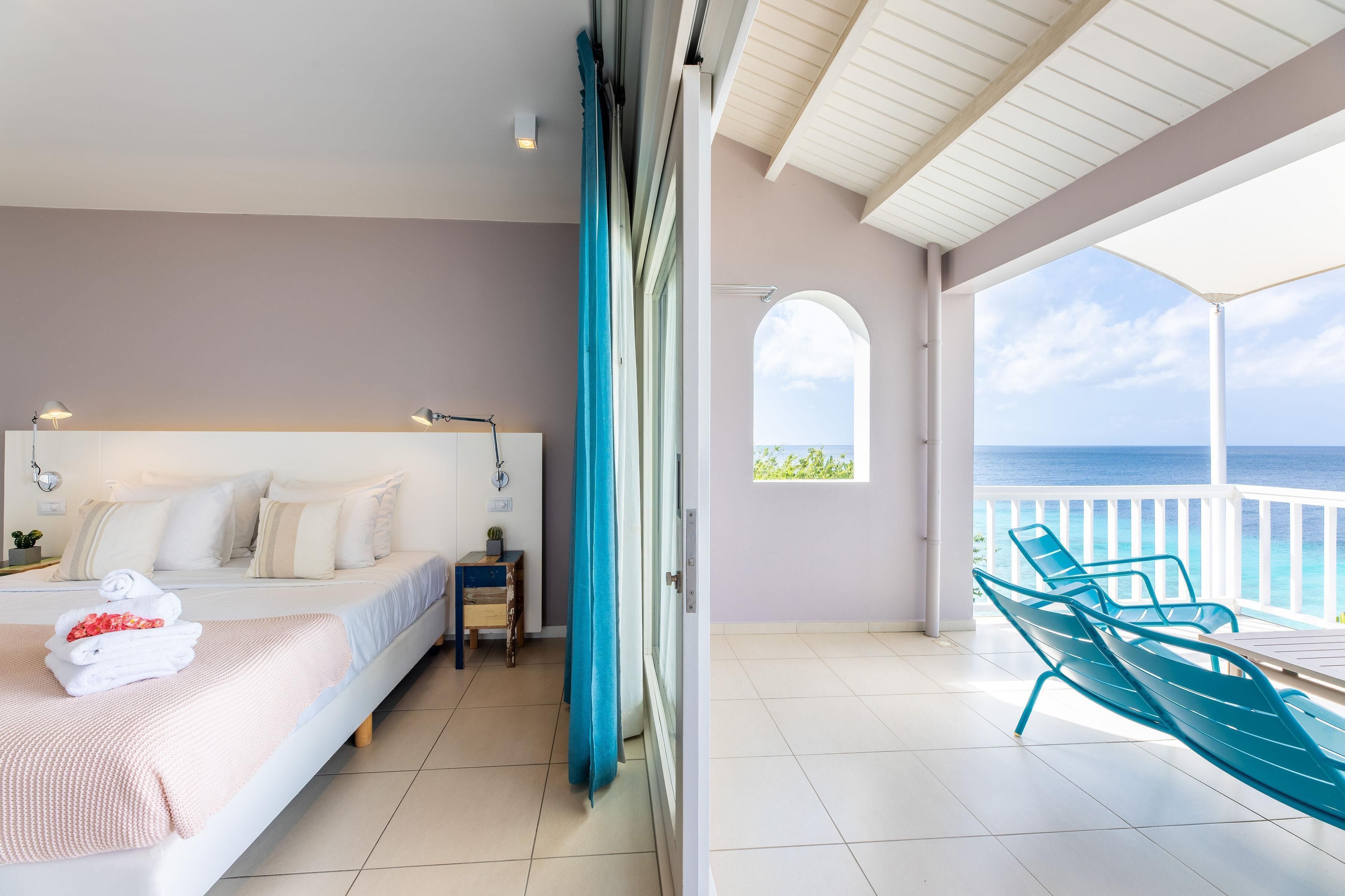 Un dormitorio con cama, mesita de noche y vista al océano.