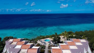 A resort with multiple buildings, a swimming pool, and a view of the ocean.