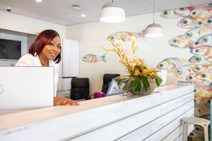 A reception desk with a floral arrangement, a fish mural, and a modern interior design.
