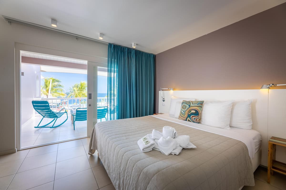 Une chambre d’hôtel avec un lit, une table de chevet, une fenêtre avec des rideaux et une vue sur l’extérieur.