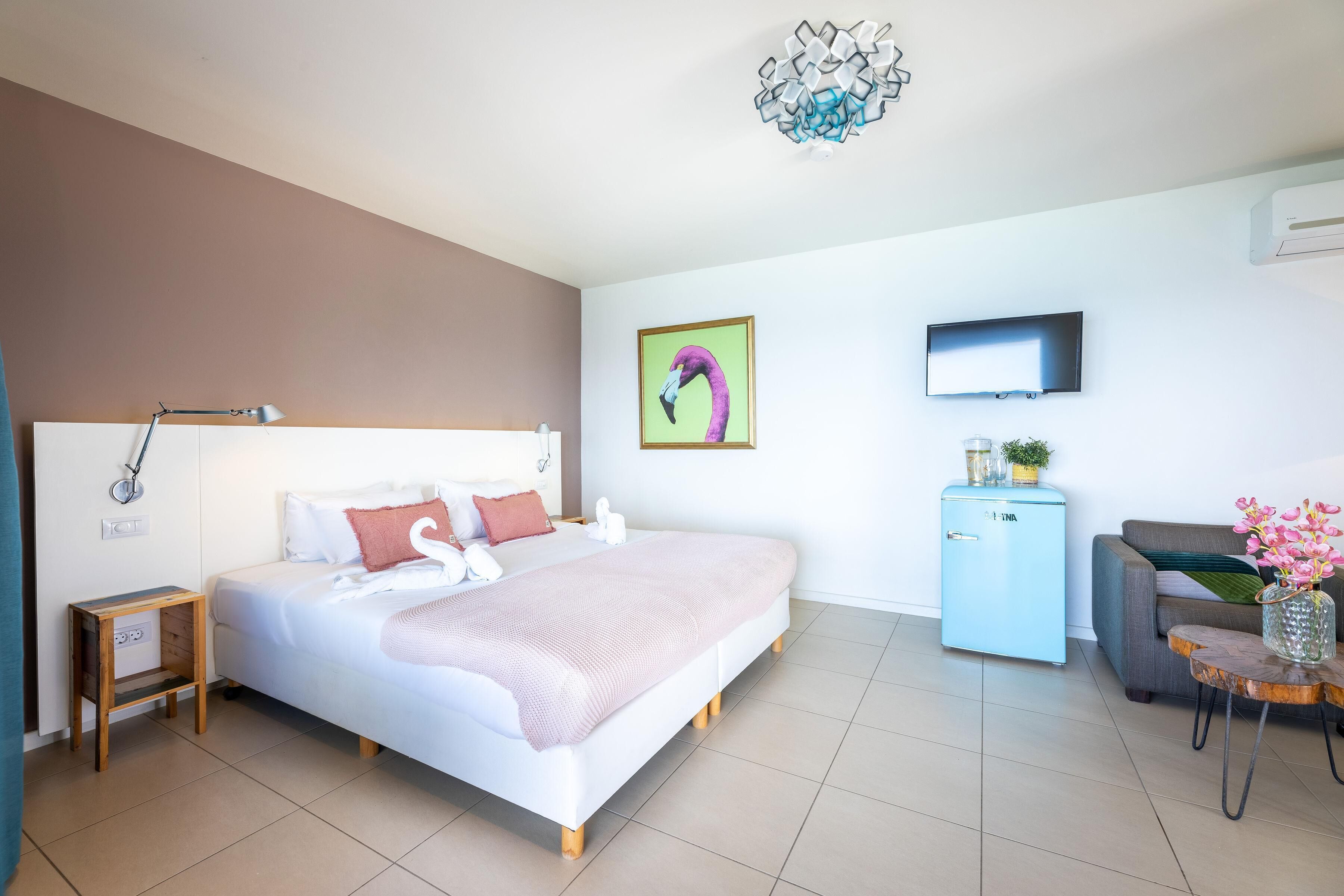A modern hotel room with a bed, bedside table, lamp, TV, and a small cabinet.