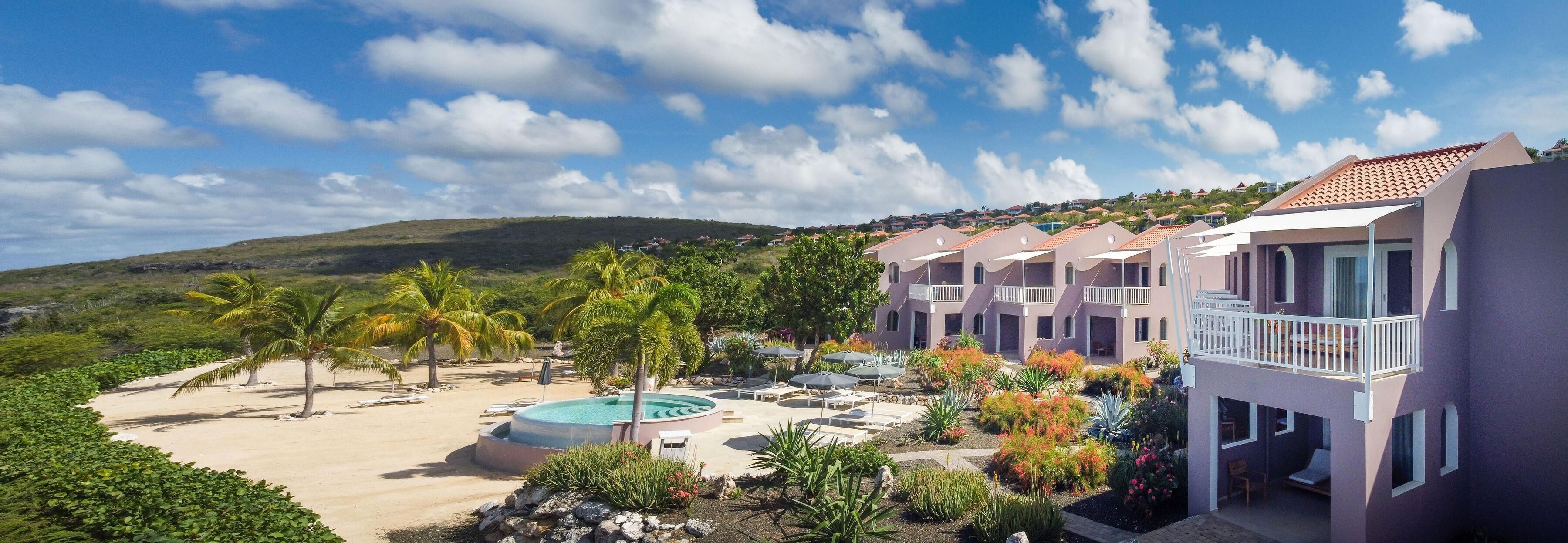 Un resort con piscina, palmeras y vistas a un paisaje montañoso.
