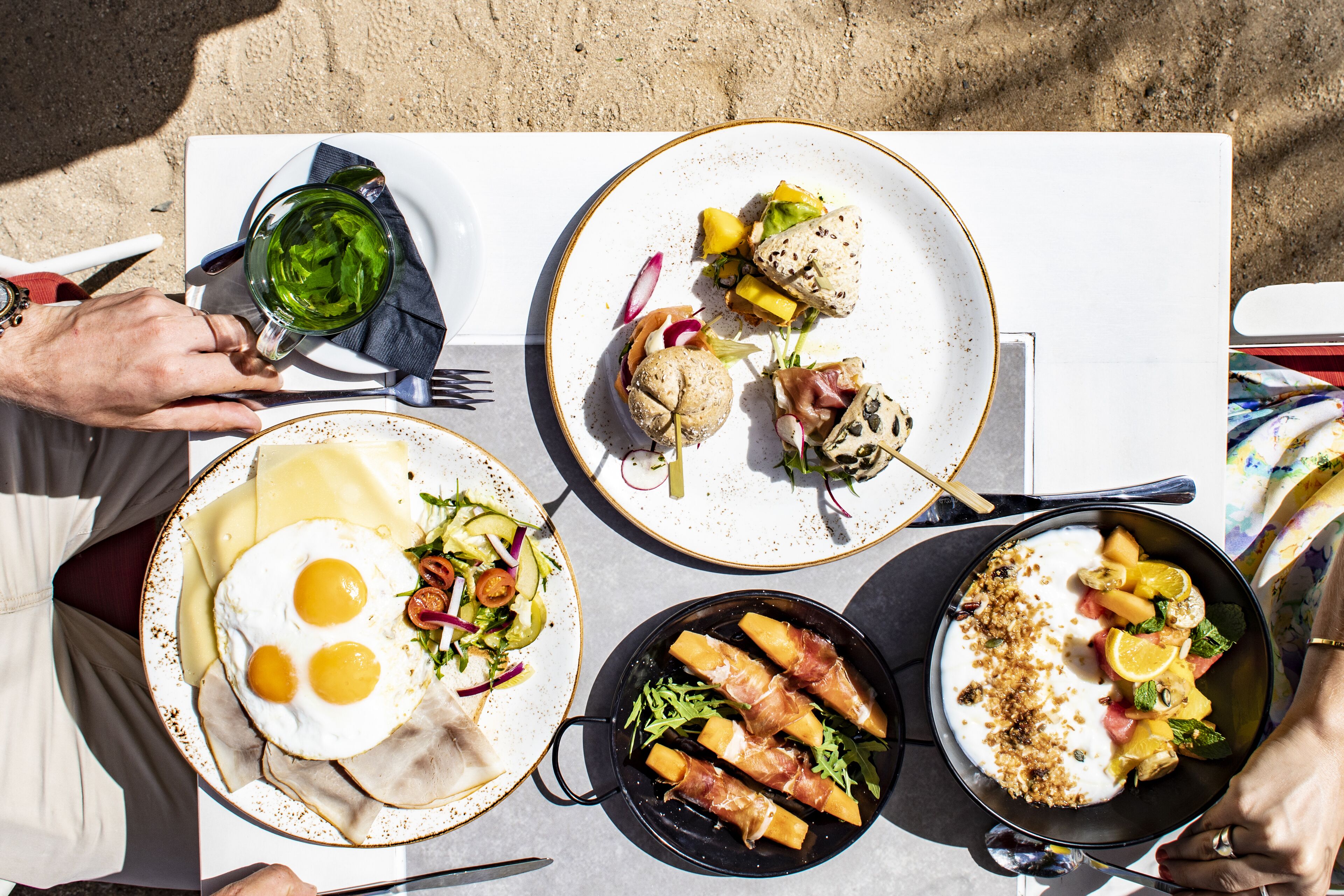 A table with various dishes including eggs, meats, and salads, suggesting a breakfast setting.