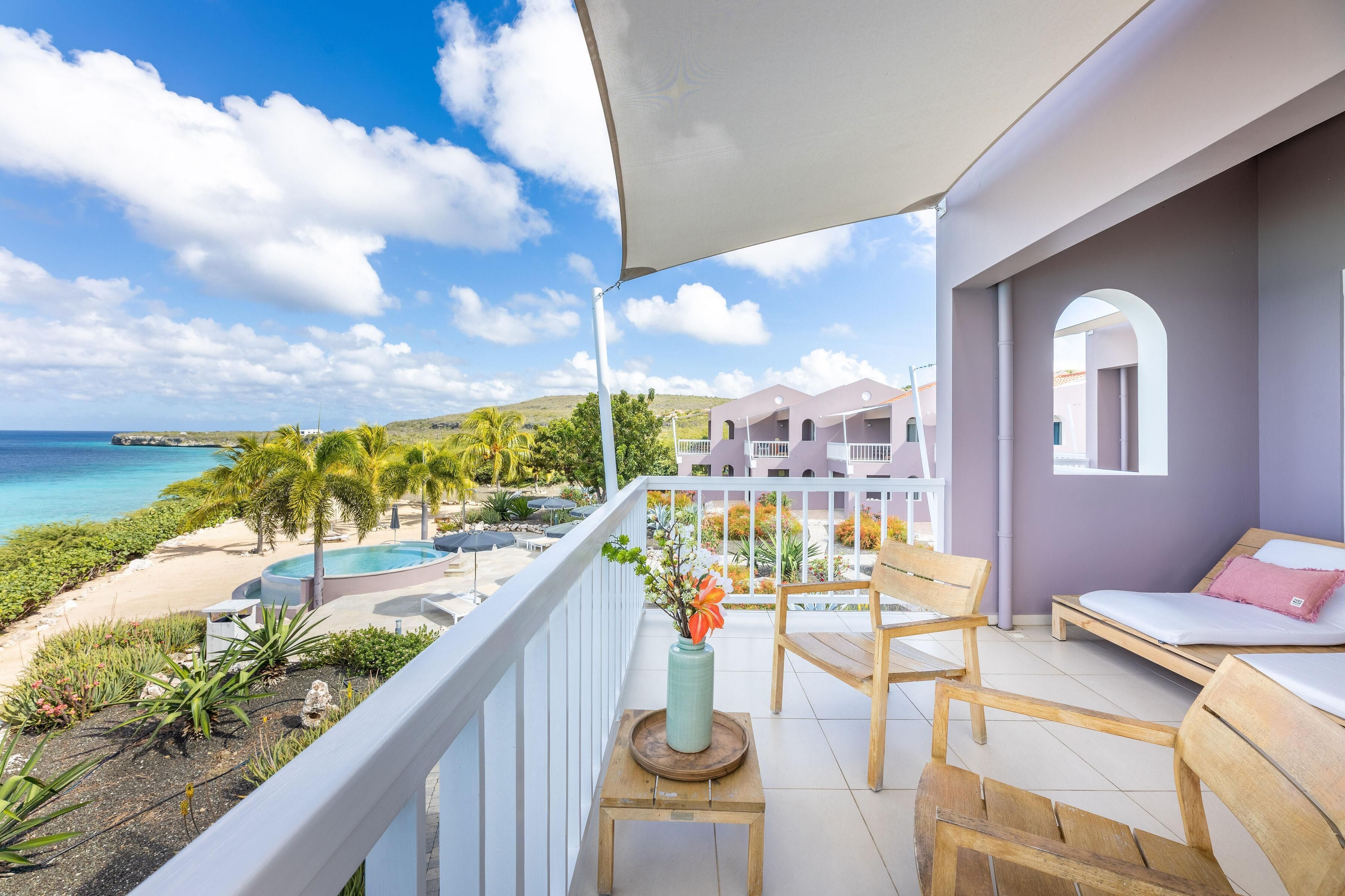 Un balcon avec vue sur l’océan, une piscine et un jardin.
