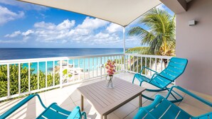 A balcony with a view of the ocean, a table with chairs, and a vase of flowers. - Coral Estate Luxury Resort (St. Marie)