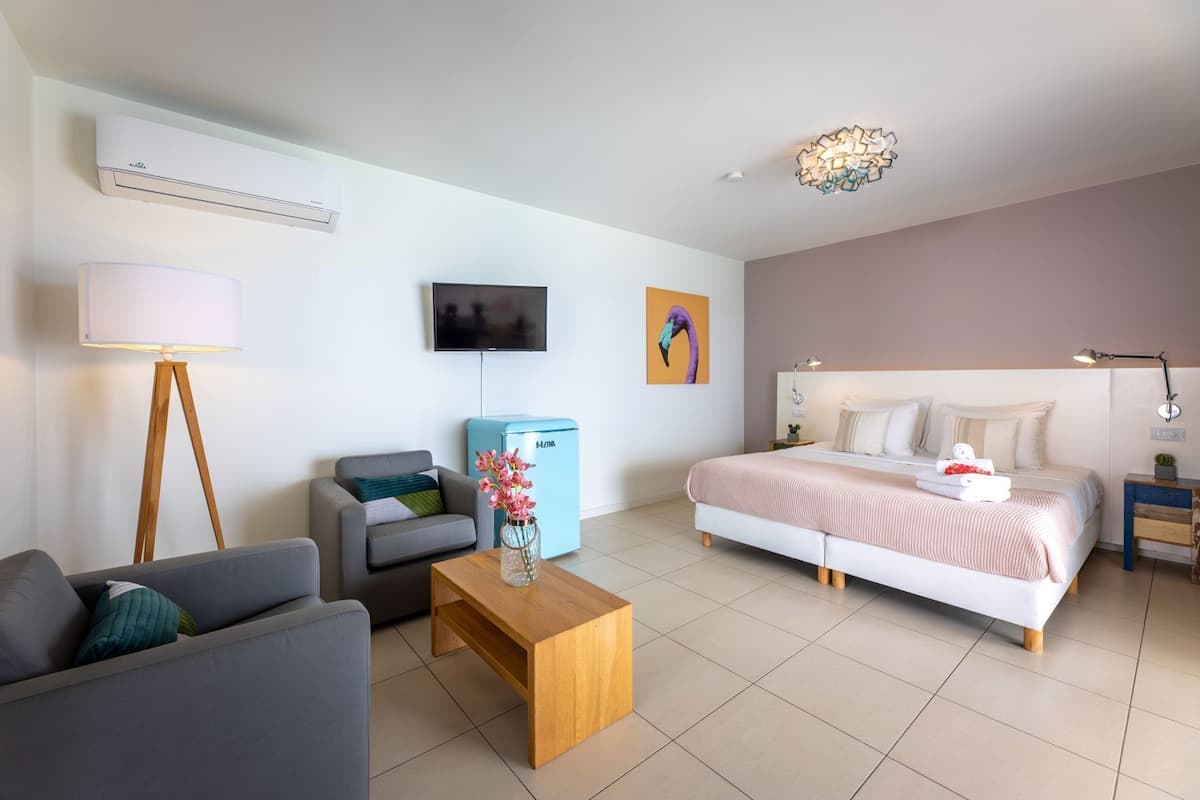 Une chambre d’hôtel moderne équipée d’un lit, d’un canapé, d’une table basse, d’une télévision et d’un mini-bar.