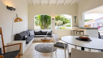 Una sala moderna con un sofá, sillas, una mesa redonda y vistas al exterior.