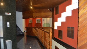 A hallway with a wooden staircase, a marble floor, and a red wall with geometric patterns. - Hotel Seoul - In Mexico City (Mexico City)