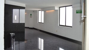 A hallway with reflective floors, large windows, and a green evacuation route sign. - Hotel Seoul - In Mexico City (Mexico City)