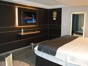 A hotel room with a large bed, a mounted TV, a small shelf, a trash can, and a door with a mirror. - Hotel Seoul - In Mexico City (Mexico City)