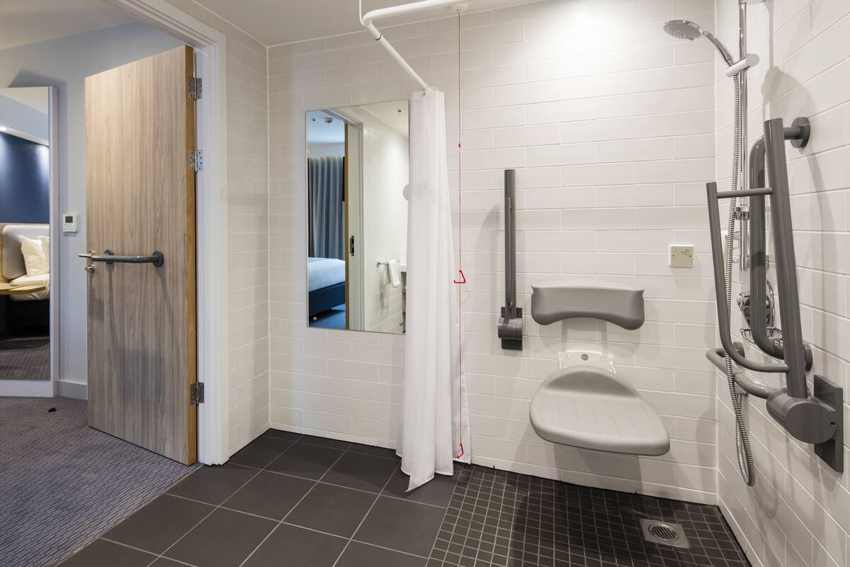 A modern bathroom with a shower, toilet, and a mirror.