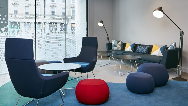 Ein moderner Lounge-Bereich mit bequemen Sitzgelegenheiten, einem Couchtisch und einer Couch mit bunten Kissen.