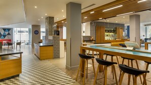 Un'area bar moderna con un lungo bancone, sgabelli da bar e un pavimento piastrellato.