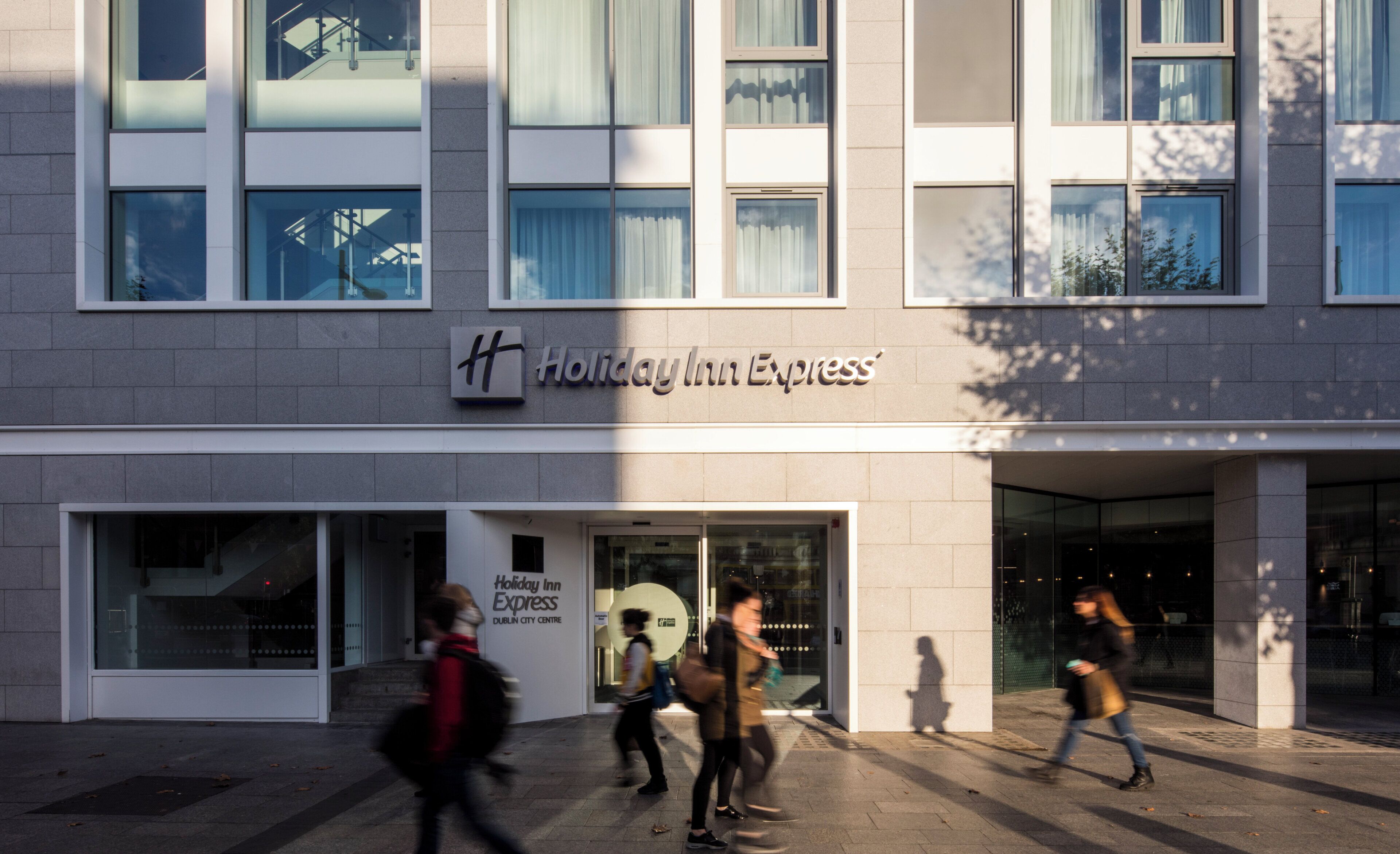 A Holiday Inn Express building with a modern facade, large windows, and a prominent logo.