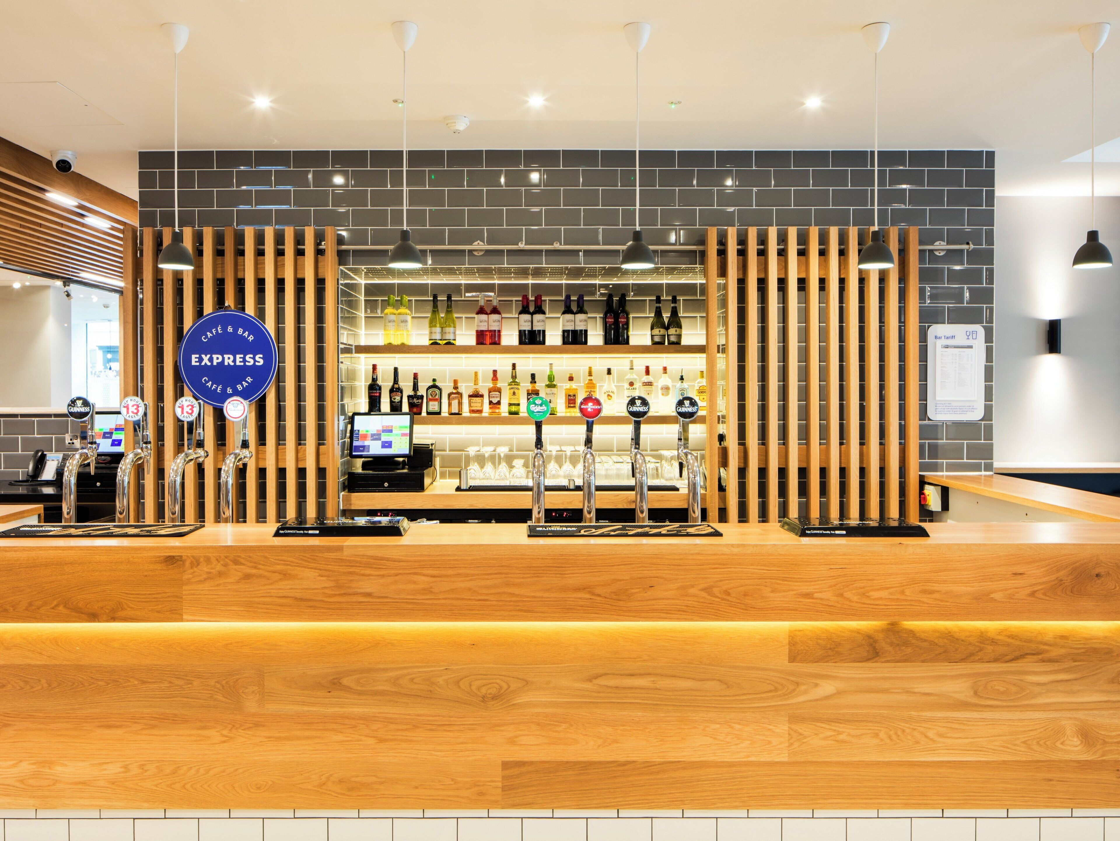Zona de bar con mostrador de madera, varias griferías y una amplia variedad de botellas.