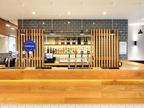A bar area with a wooden counter, multiple taps, and a variety of bottles.