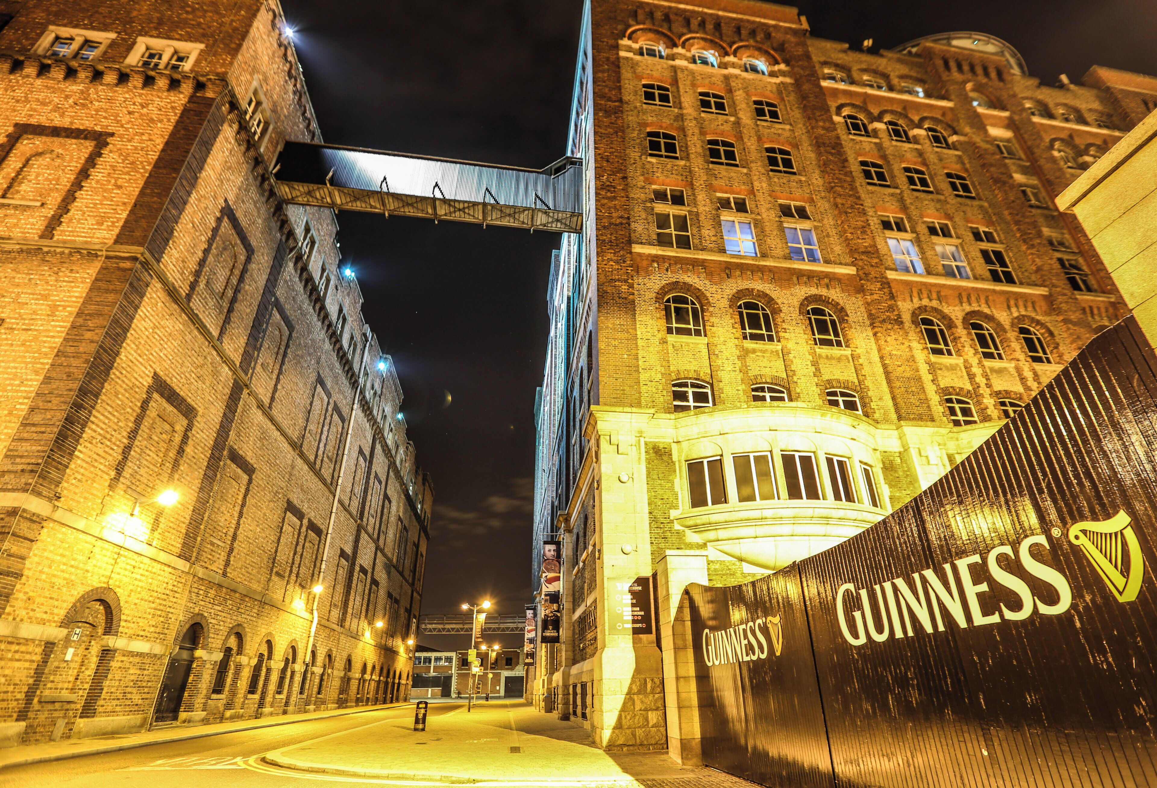 A nighttime street view with a large building featuring a prominent Guinness sign.