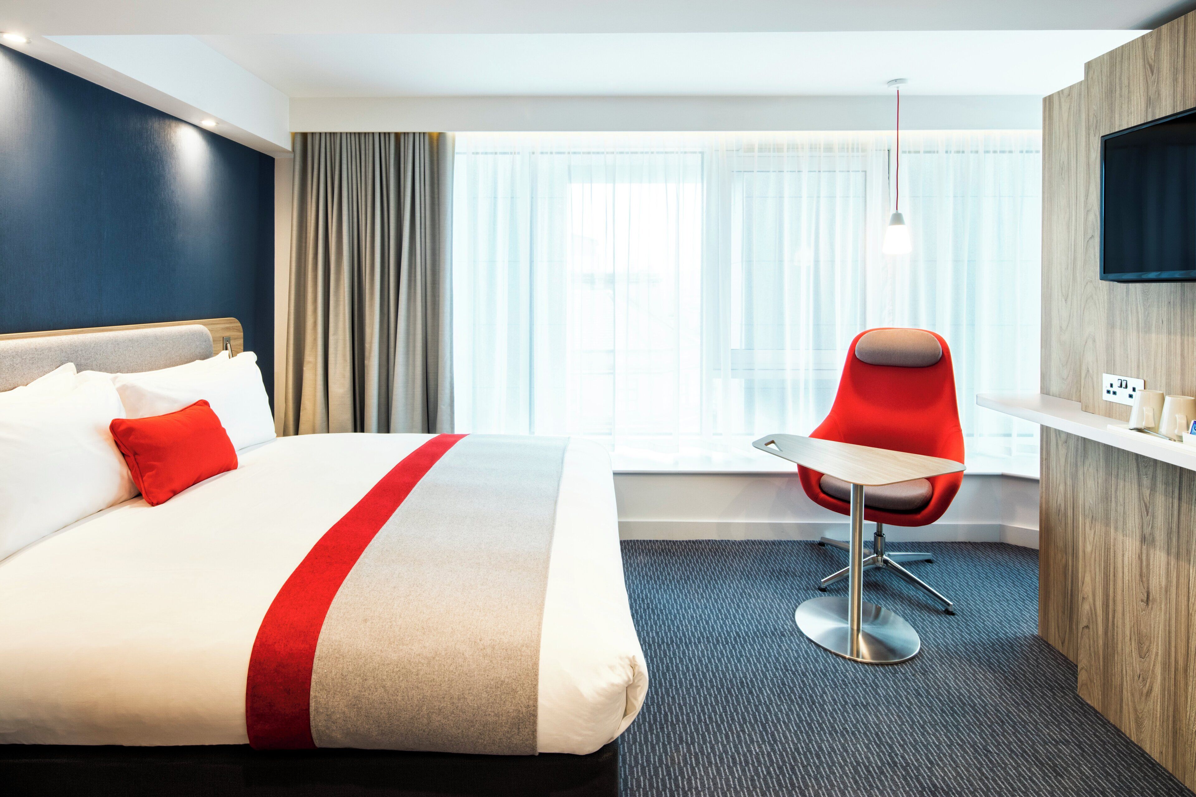 Ein Hotelzimmer mit einem großen Bett, einem Schreibtisch und einem Sessel.