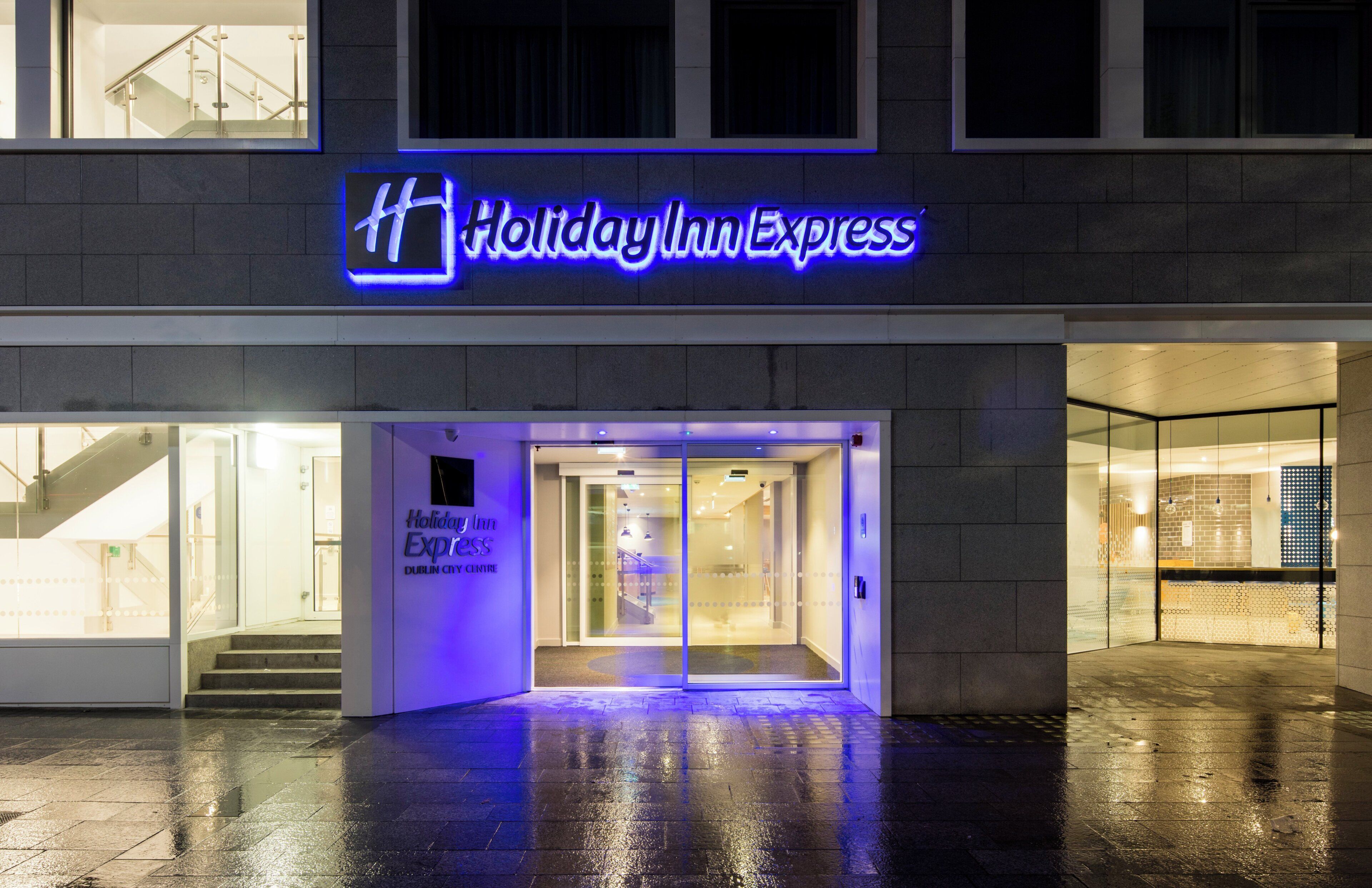 L'esterno di un Holiday Inn Express con ingresso in vetro e un cartello sopra.