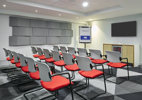 A conference room with rows of chairs, a projection screen, and a podium.