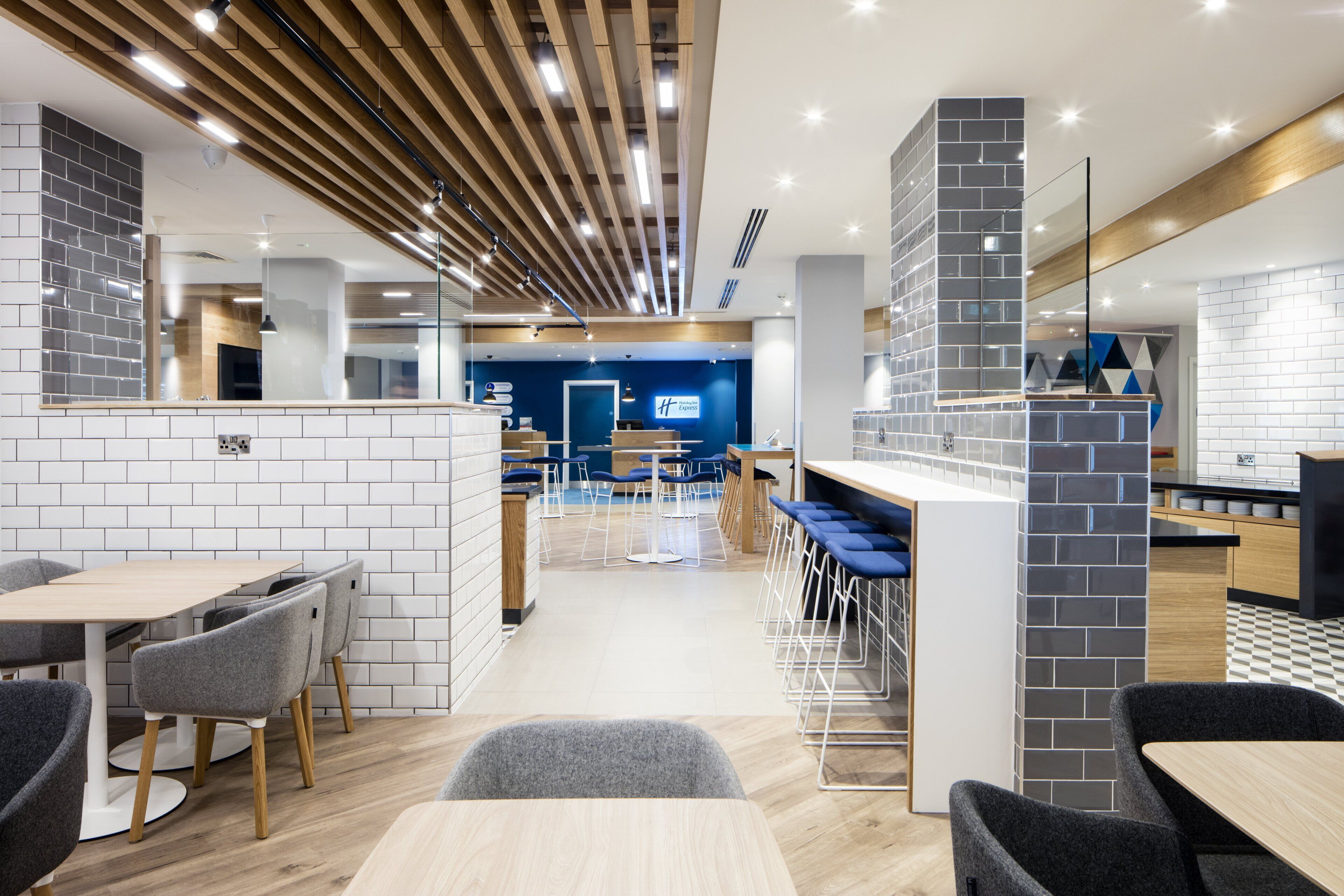 A modern hotel lobby with a reception desk, seating area, and a bar.