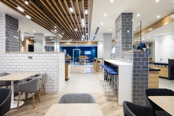 Un hall d’hôtel moderne comprenant un comptoir d’accueil, un espace salon et un bar.