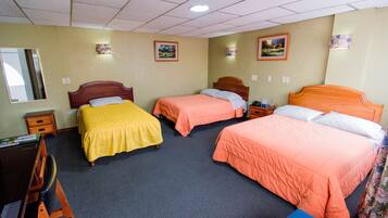 A hotel room with three single beds, a desk with a chair, and a small table.