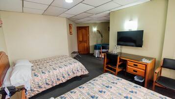 Een hotelkamer met twee bedden, een bureau, een stoel, een televisie en een klein tafeltje.