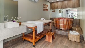 Un baño moderno con una bañera de madera, un espejo grande, un lavabo y un banco.
