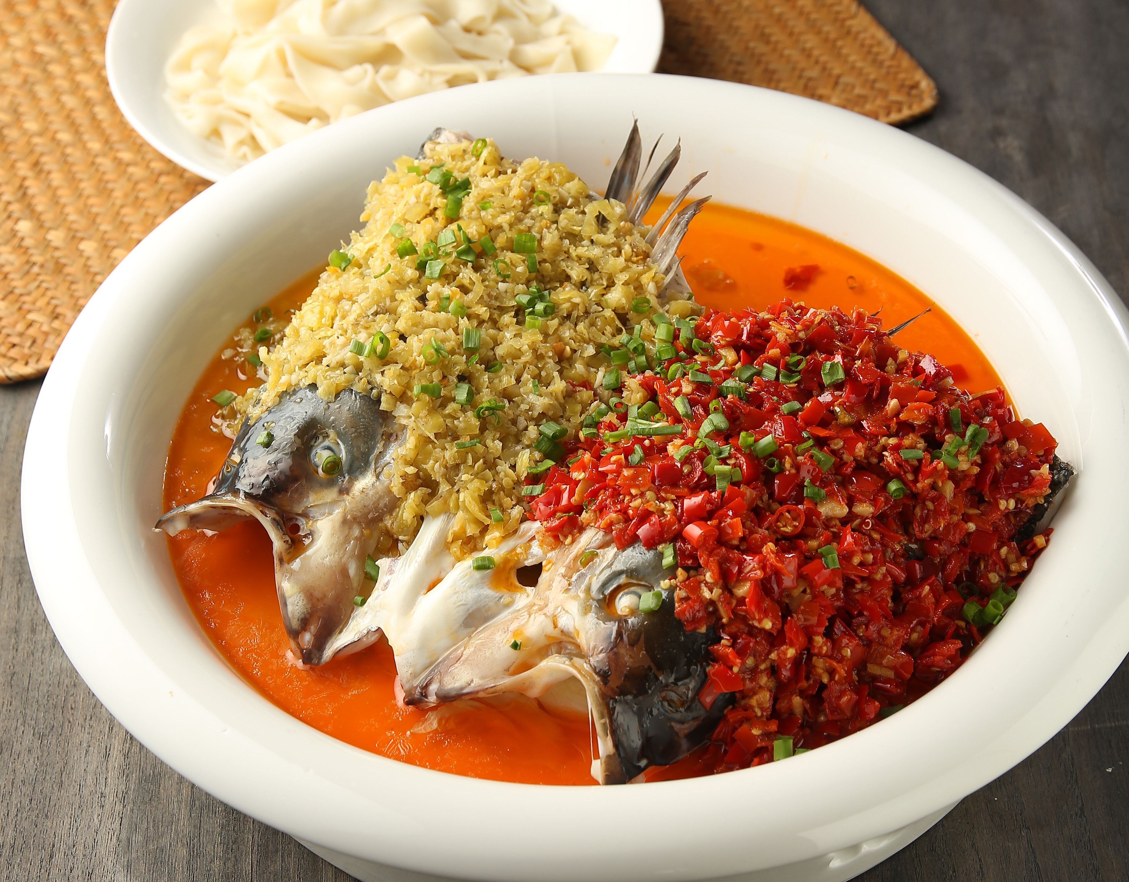 A bowl of fish with rice and a spicy red sauce.