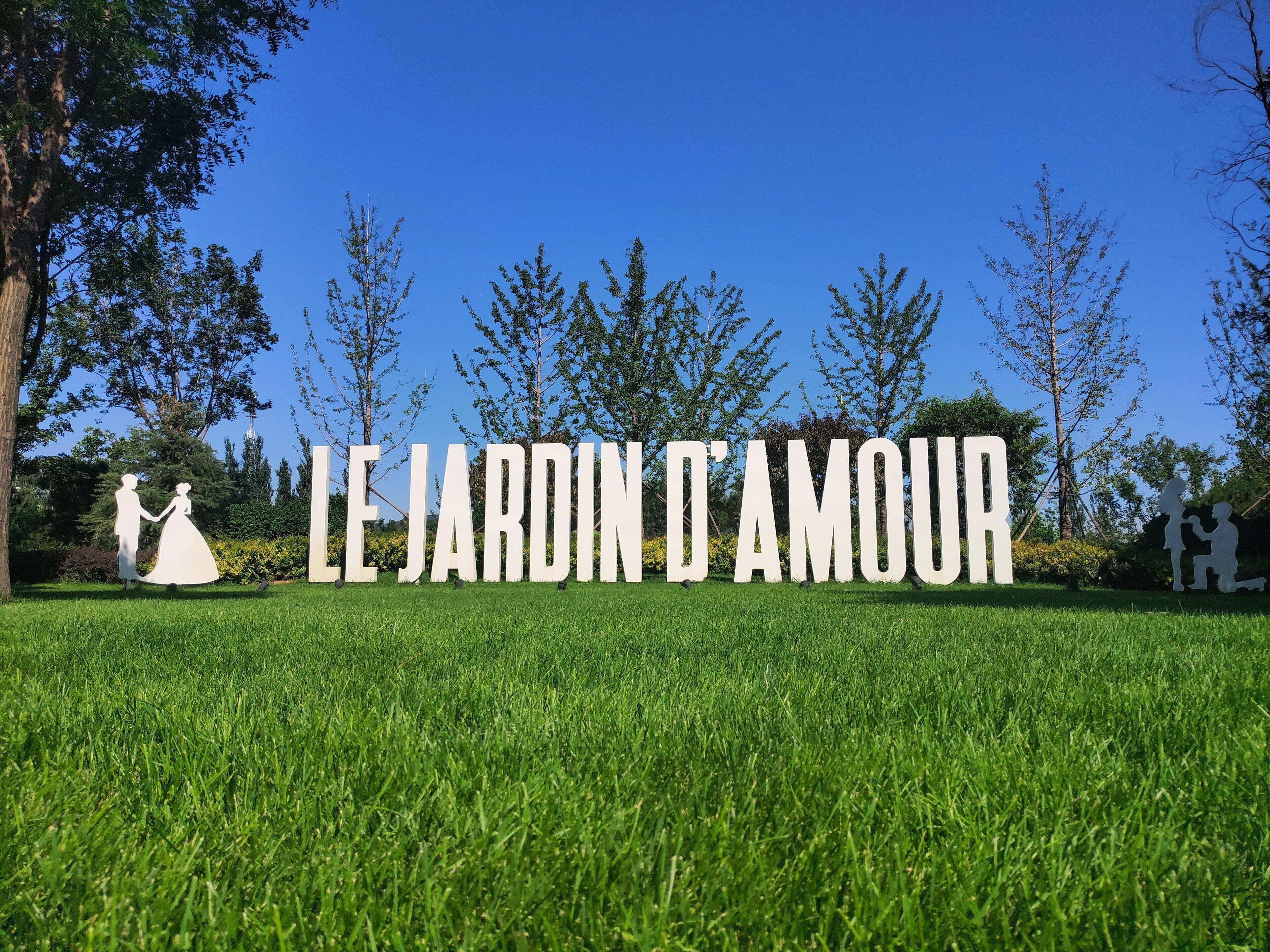 A sign with the text "LE JARDIN D'AMOUR" in a park setting.