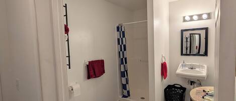 A modern bathroom with a toilet, shower, sink, and vanity.