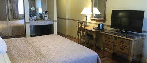 A hotel room with a bed, a desk, a television, and a mirror.