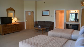 A hotel room with two beds, a TV, a dresser, a sofa, and a small table.