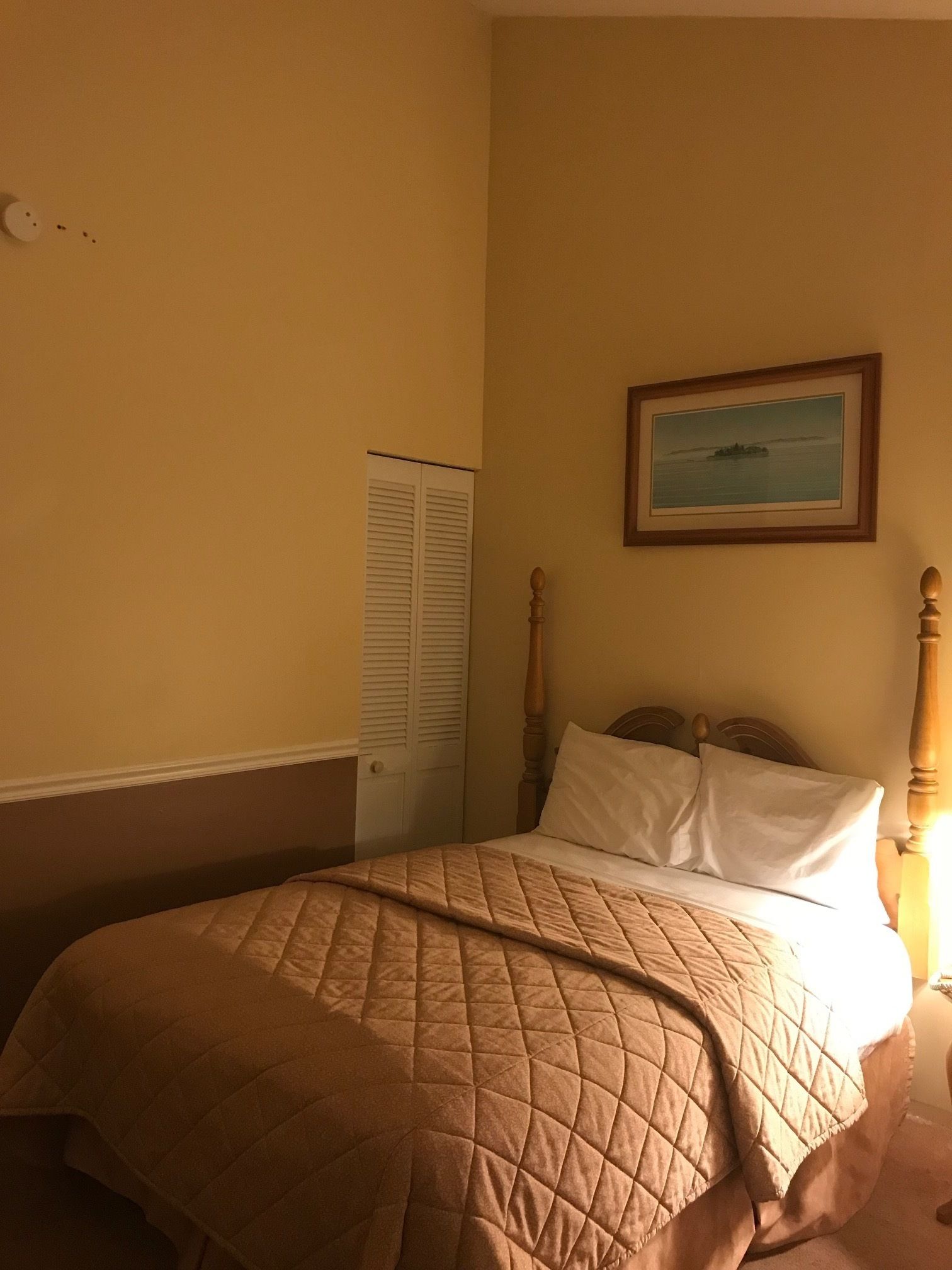 Un dormitorio con una cama, una puerta y un cuadro en la pared.