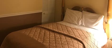 Un dormitorio con una cama, una puerta y un cuadro en la pared.