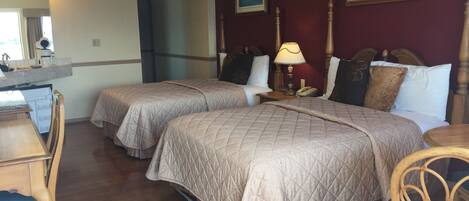 A hotel room with two beds, wooden furniture, a desk, and a mirror.