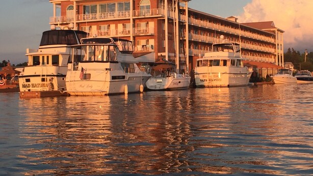 A waterfront hotel with multiple boats docked in front. - Riveredge Resort (Alexandria Bay)