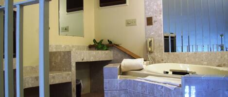 A bathroom with a bathtub, a sink, a mirror, and a shower area.
