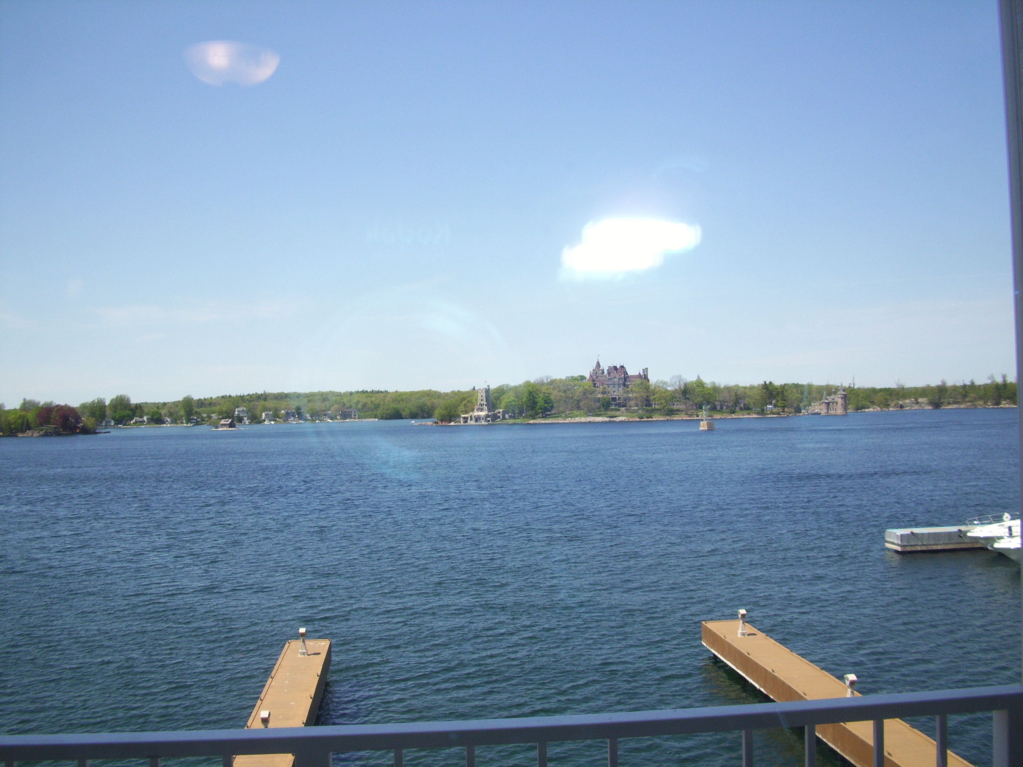 Une vue d’un lac paisible, avec un château lointain, un quai et un bateau.