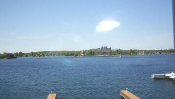 Une vue d’un lac paisible, avec un château lointain, un quai et un bateau.