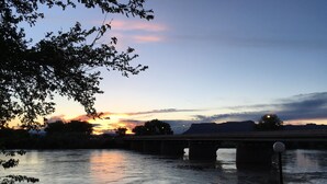 Un atardecer sobre un río con un puente y árboles.