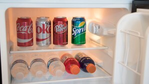 Un refrigerador con diversas bebidas, incluyendo Coca-Cola, Diet Coke, Dr. Pepper y Sprite.
