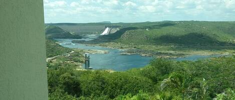 A dam with water flowing over it, surrounded by lush greenery and hills.