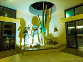 Zona de recepción con una exhibición central de estatuas, un amplio ventanal y una decoración de diseño moderno.