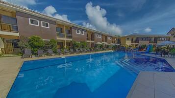 Piscina com espreguiçadeiras e guarda-sóis, cercada por edifícios altos com varandas.