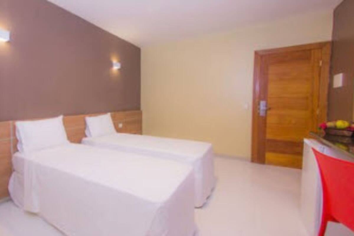 A hotel room with two beds, a desk, and a chair.